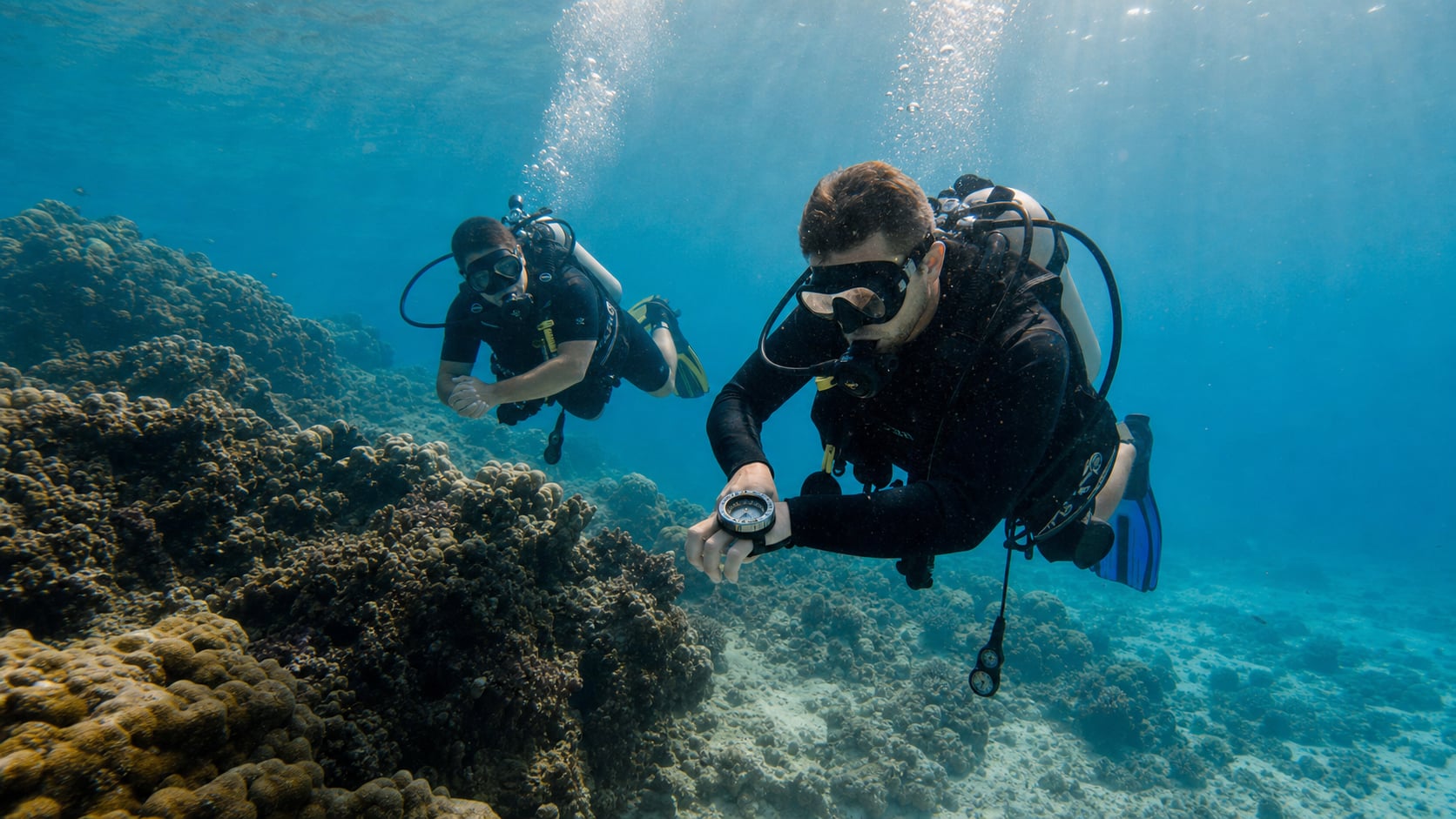 Taucher hält Kompass unter Wasser beim Navigation Specialty Kurs am Korallenriff vor Koh Tao